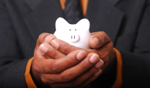 Cupped hands holding a small white piggy bank